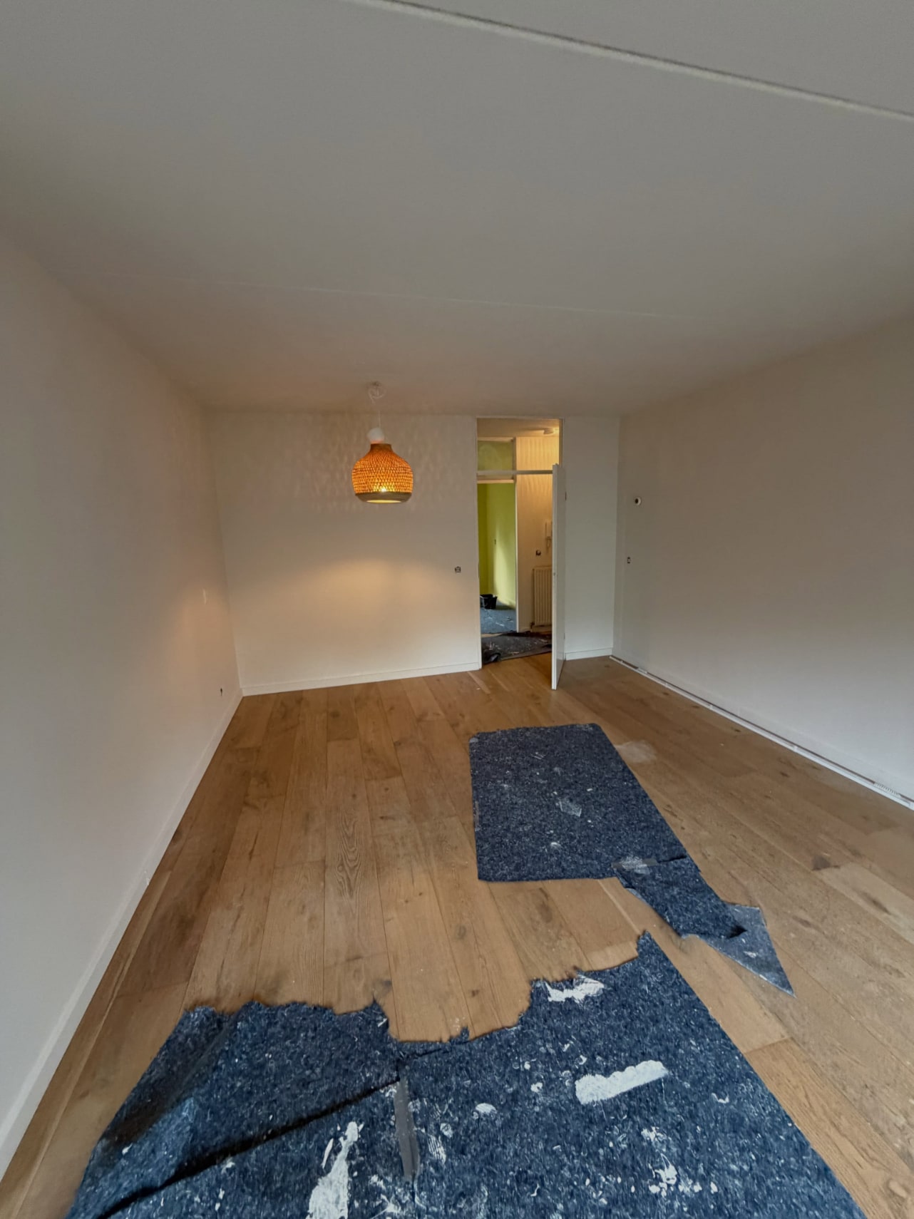 Lege kamer met strak wit gespoten wanden en plafond en een eiken vloer
