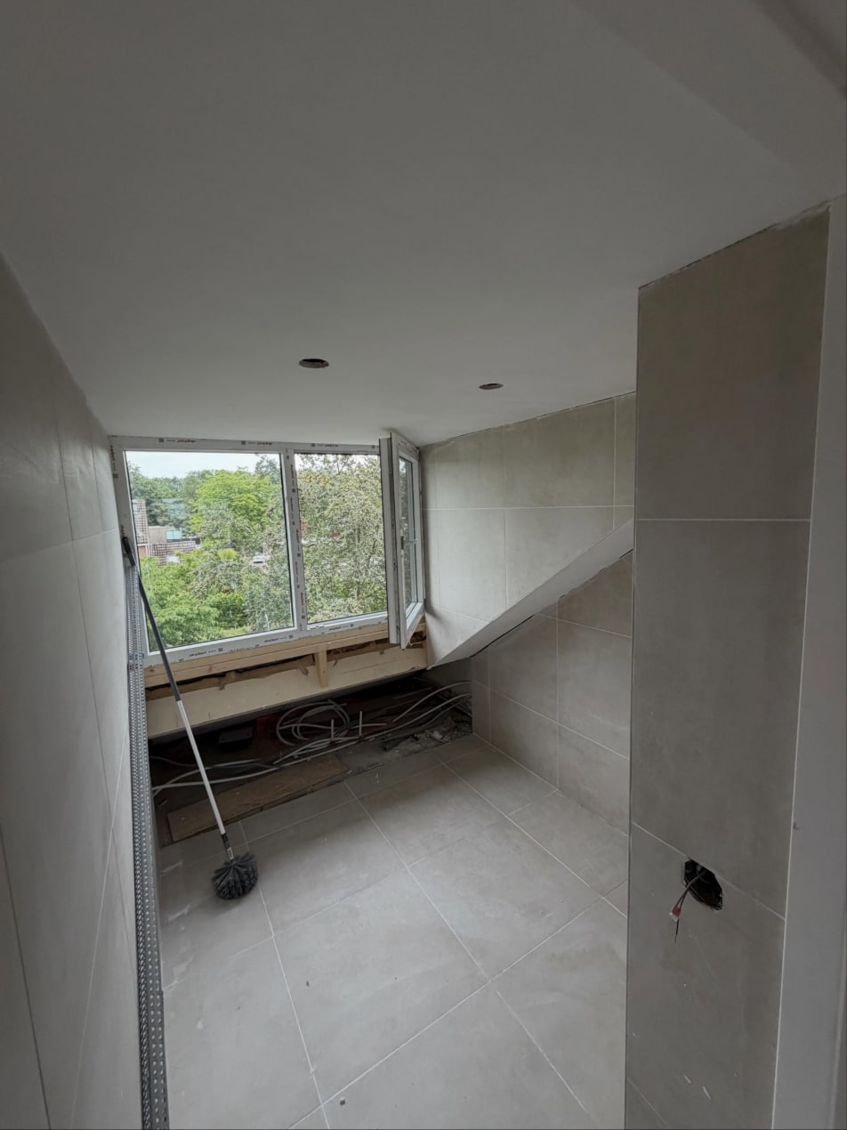 Badkamer onder een dakkapel met een strak plafond met inbouwspots en betegelde wanden