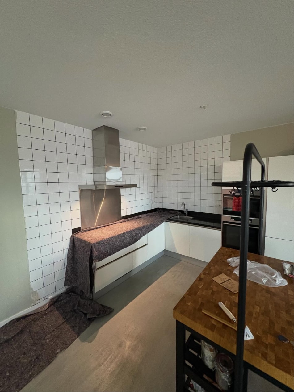 Keuken met een strak gestuct plafond en wanden boven wit tegelwerk