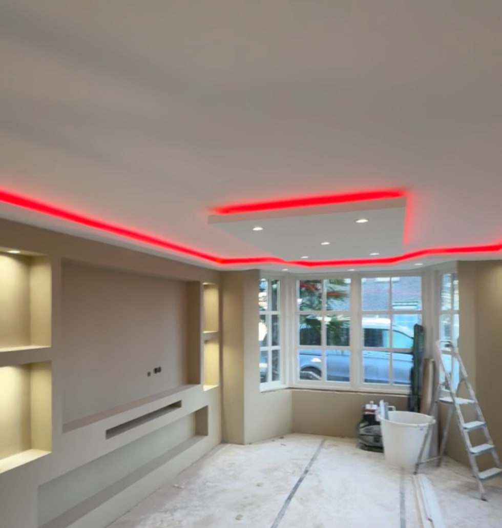 Gestucte woonkamer met een verlaagd plafondeiland, ledverlichting in de koof en een tv-wand met verlichte nissen